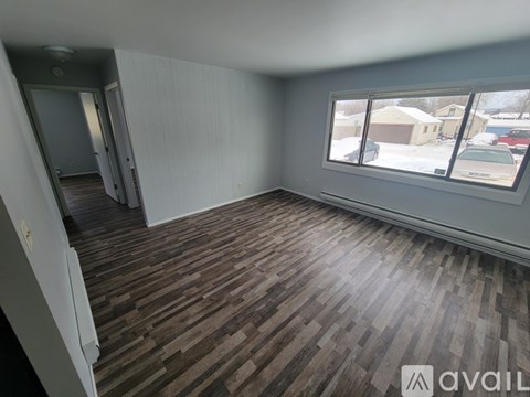 A room with wooden flooring and a window overlooking a parking lot.