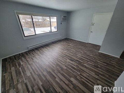 A room with wooden flooring and a window overlooking a snowy street.