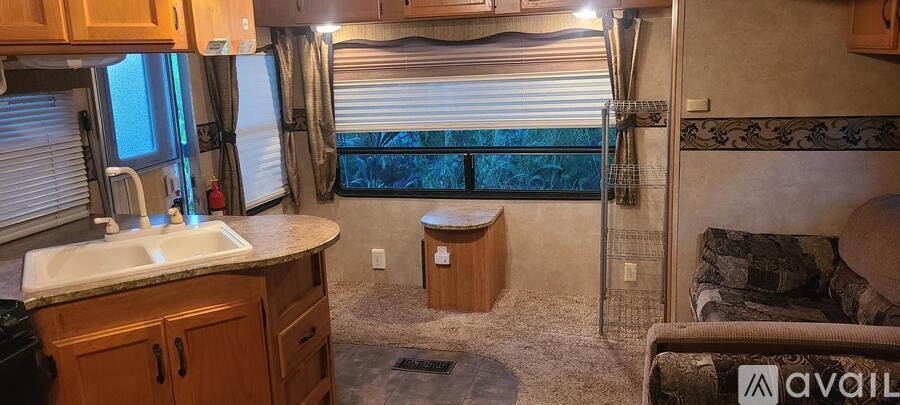 A kitchen area with a sink and a window with blinds.