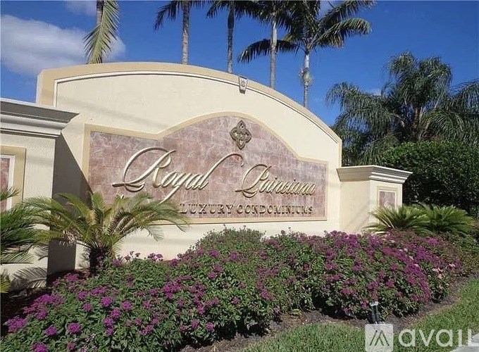 A sign for Royal Palm Estates in front of some trees.