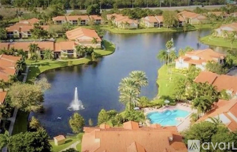 A bird's eye view of a residential area with a lake and a fountain.