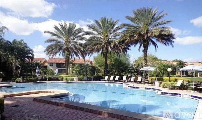A pool surrounded by palm trees and lounge chairs.