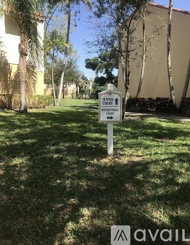 A sign in the grass that says Tennis Court Racquetball Court.