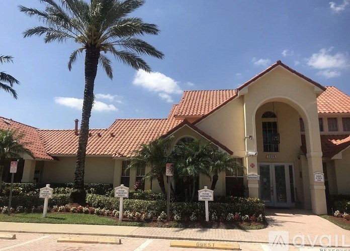 A building with a red roof and a palm tree in front.