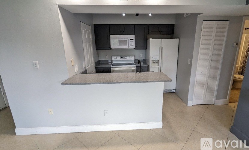 A kitchen with a white countertop and black cabinets.