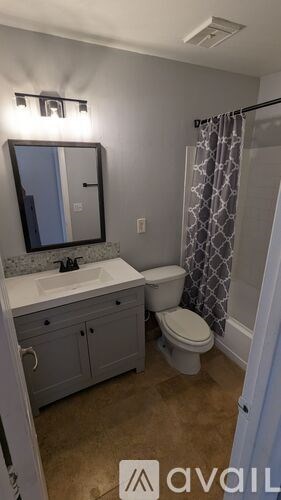 A bathroom with a toilet, sink, and mirror.