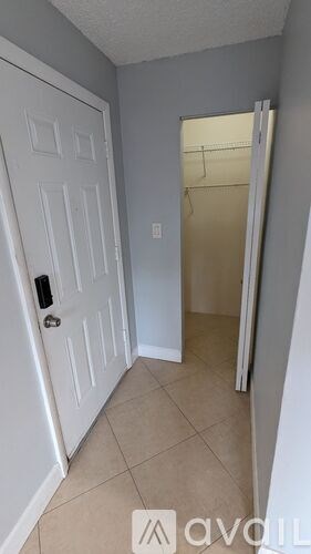A hallway with a white door and a white wall.
