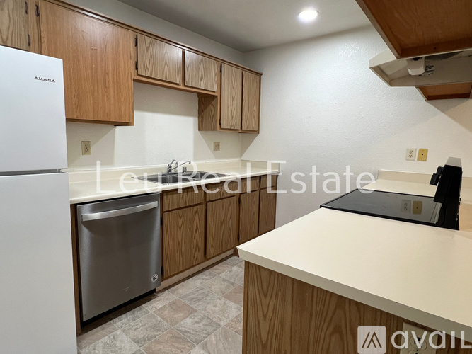 A kitchen with a white fridge, wooden cabinets, and a white countertop.