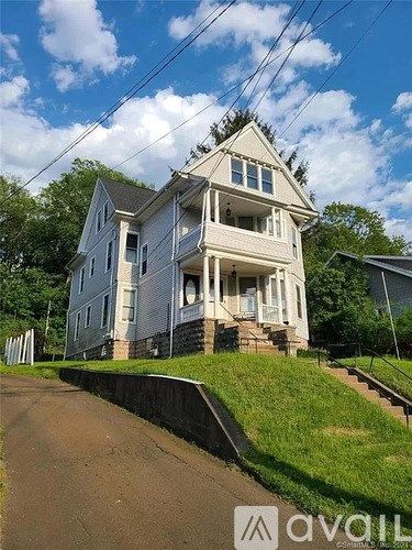 A two-story house with a white exterior and a large front porch.