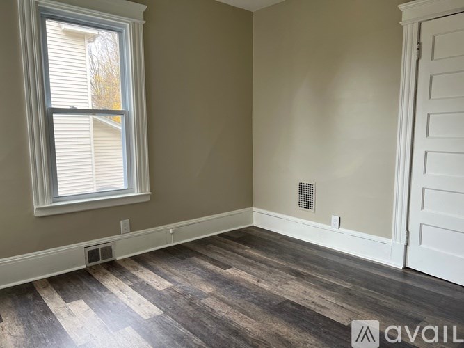 A room with a window and a wooden floor.