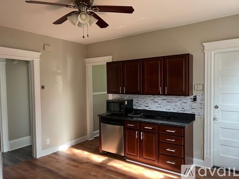 A kitchen with brown cabinets and a black countertop.