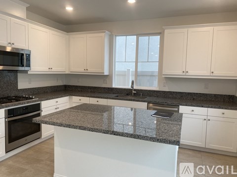 A kitchen with white cabinets and a granite countertop.