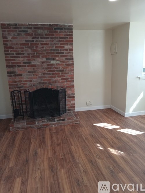 A room with a brick fireplace and wooden floors.