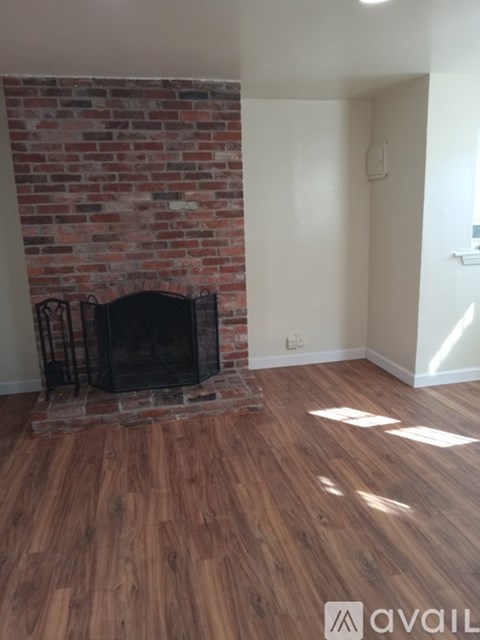 A room with a brick fireplace and wooden floors.