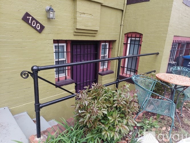 A yellow building with a black railing and a purple door.