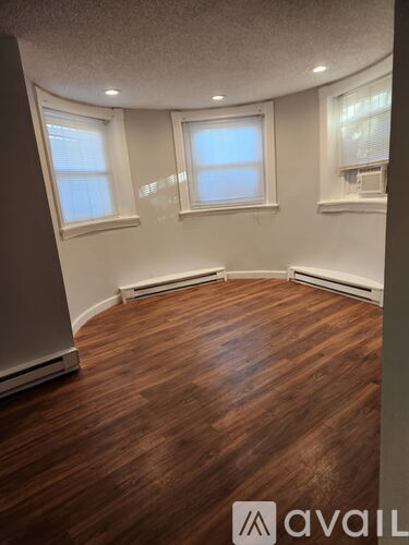 A room with wooden floors and two windows.