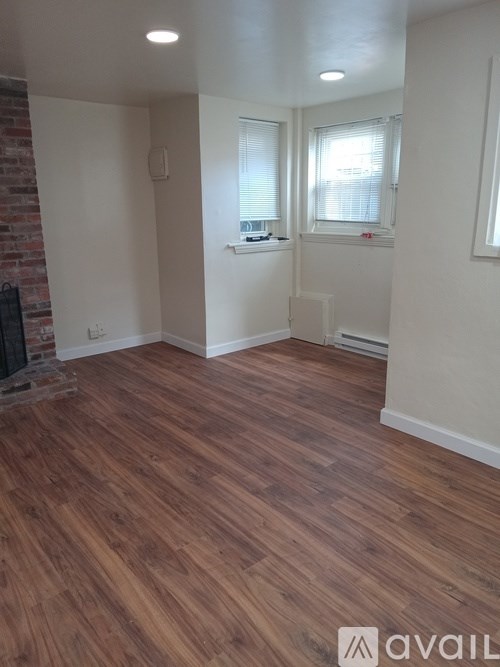 A room with wooden flooring and a brick wall.