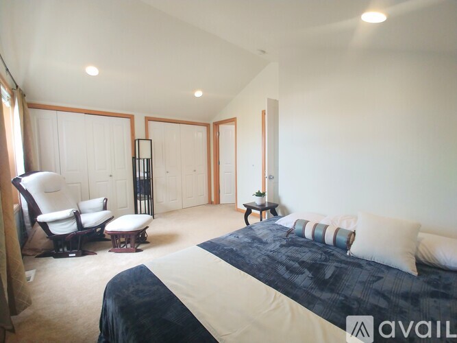 A bedroom with a large bed and a chair.