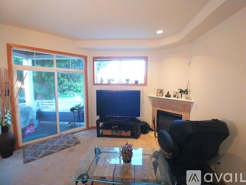 A living room with a glass coffee table and a black leather chair.