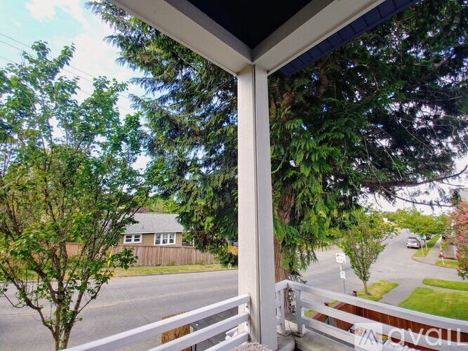A view from a porch looking out at a street with trees and houses.