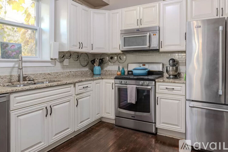 A kitchen with white cabinets and a stainless steel refrigerator.