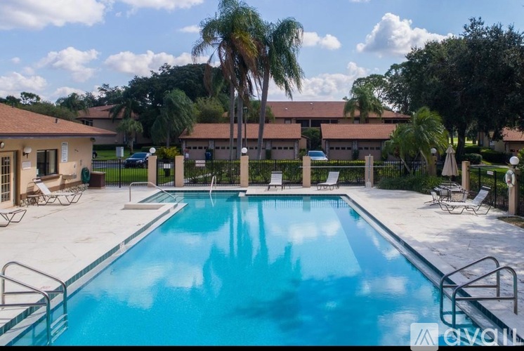 A swimming pool surrounded by palm trees and lounge chairs.
