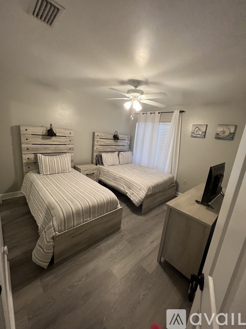 A bedroom with two beds and a television.