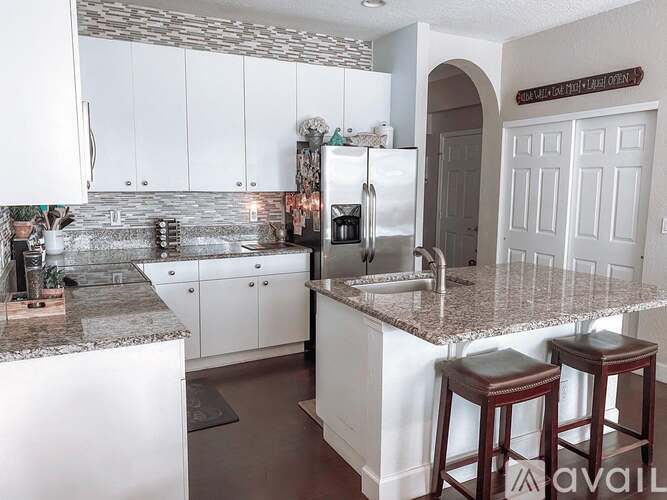 A kitchen with white cabinets and a marble countertop.
