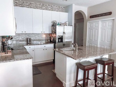 A kitchen with white cabinets and a marble countertop.