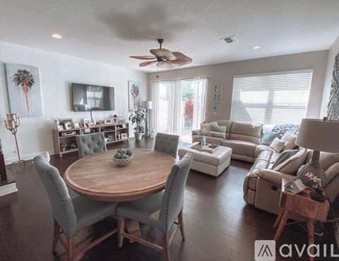 A living room with a wooden table surrounded by grey chairs.