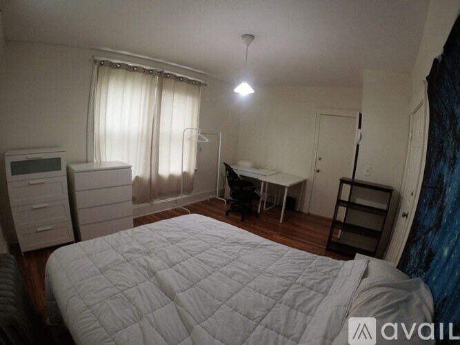 A bedroom with a large bed and a desk in the corner.
