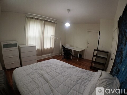 A bedroom with a large bed and a desk in the corner.