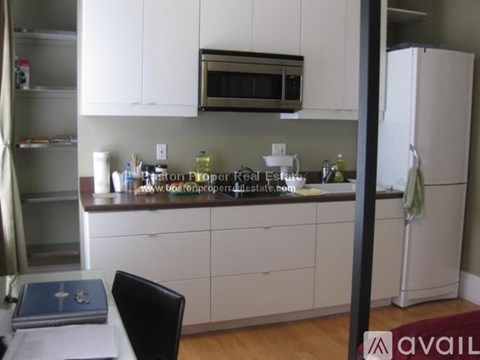 A kitchen with white cabinets and a black chair.