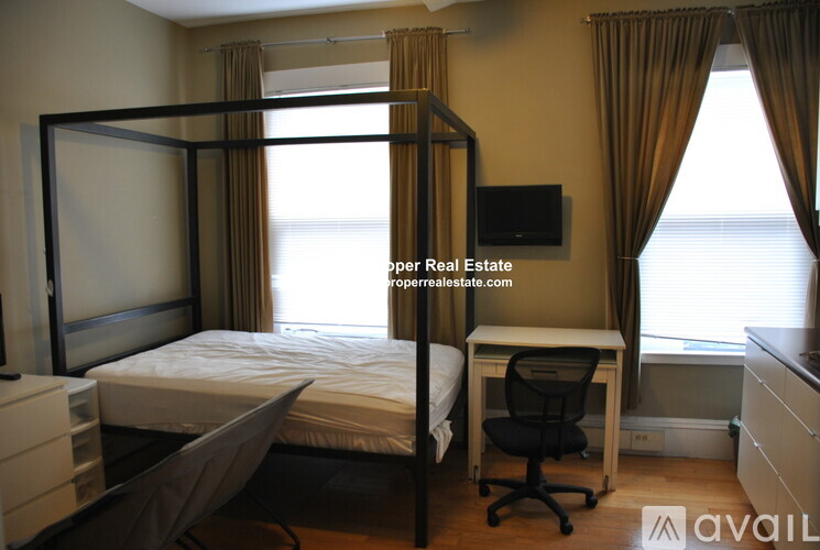 A bedroom with a four poster bed and a desk with a chair.