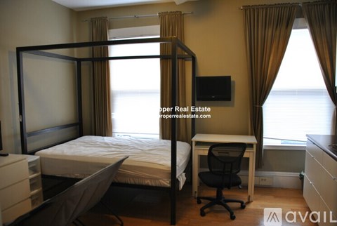 A bedroom with a four poster bed and a desk with a chair.