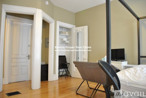 A bedroom with a bed, chair, and mirror.
