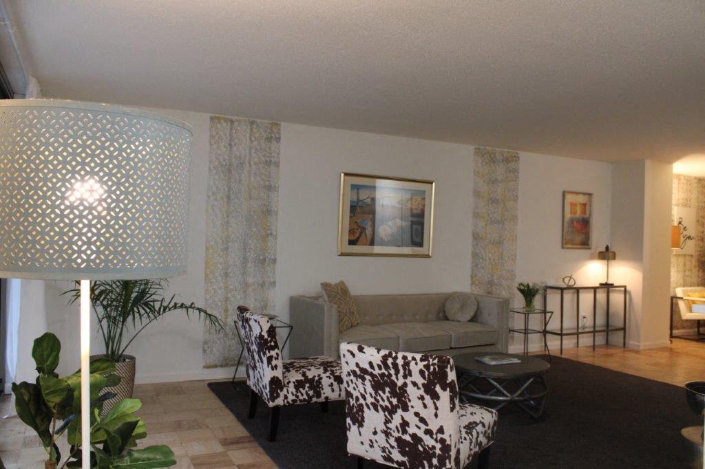 a living room with a couch and chairs and a lamp