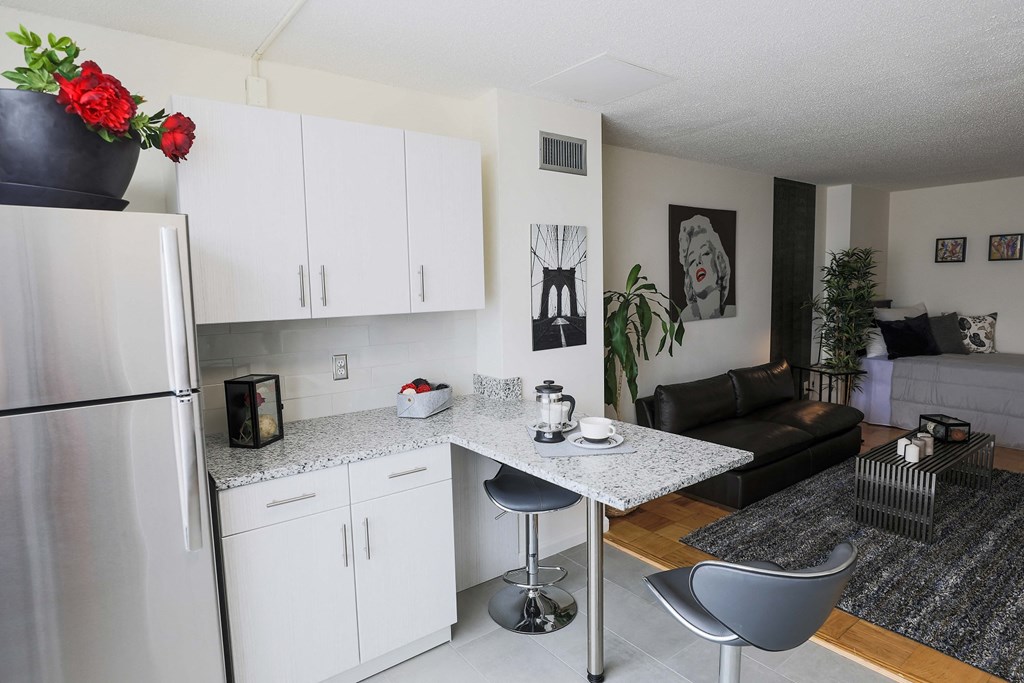 a kitchen and living room with white cabinets and a granite counter top
