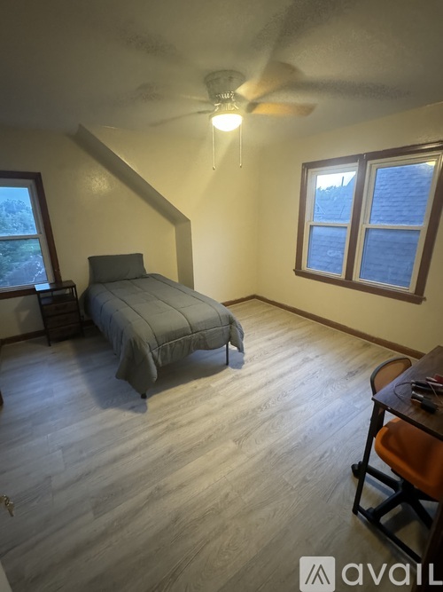 A bedroom with a bed, a ceiling fan, and a window.
