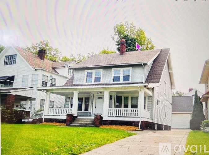 A white house with a porch and a chimney.
