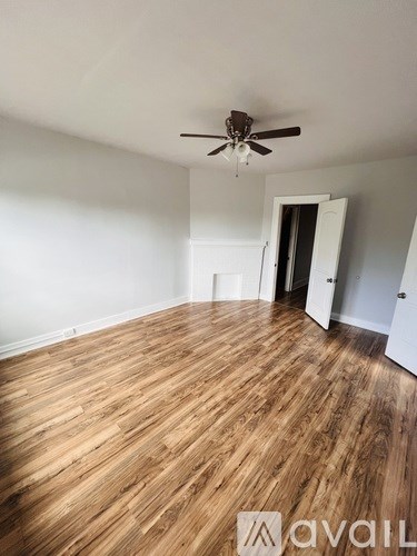 A room with wooden flooring and a ceiling fan.