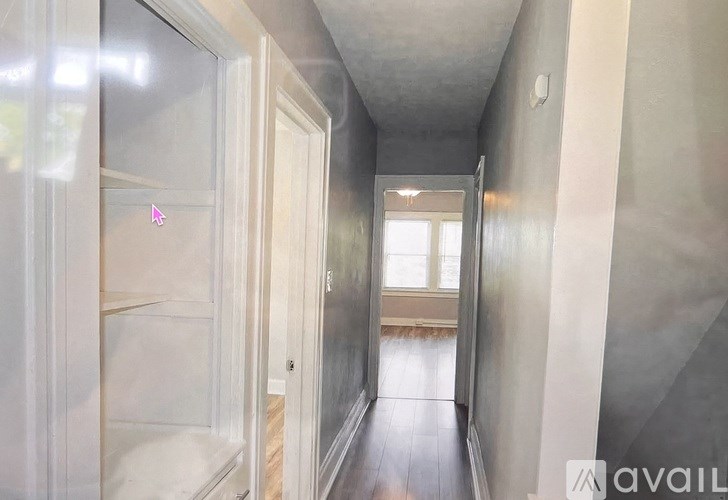 A hallway with a glass door and a wooden floor.