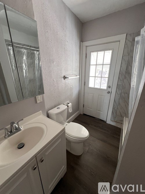 A bathroom with a toilet, sink, and mirror.