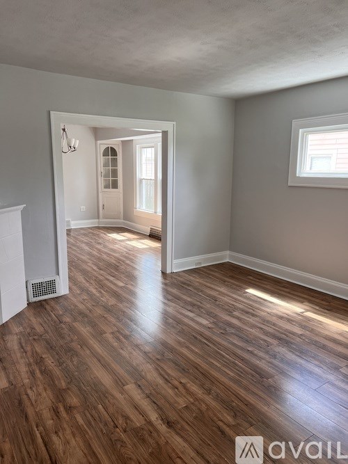 A room with wooden flooring and a window on the wall.