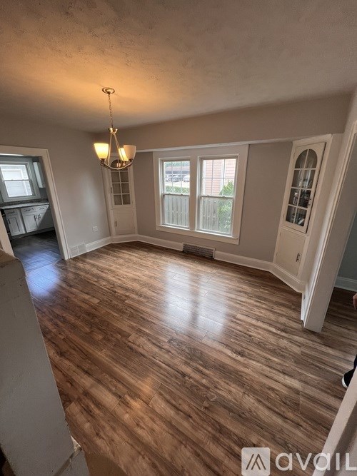 A room with wooden flooring and a chandelier.