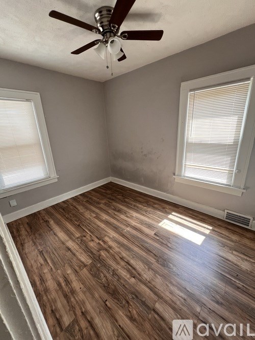 A room with wooden flooring and a ceiling fan.