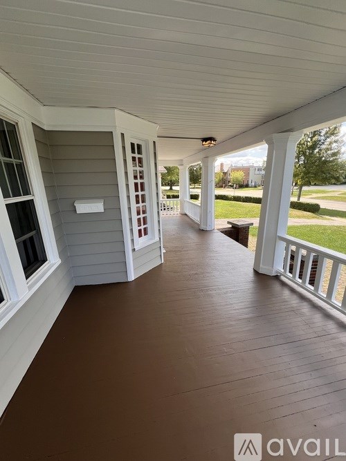 A porch with a white ceiling and a brown floor.
