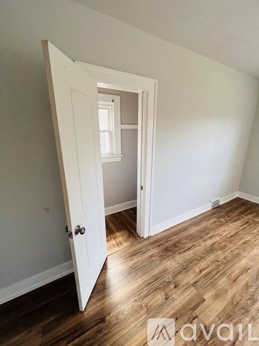 A room with a white door and wooden flooring.