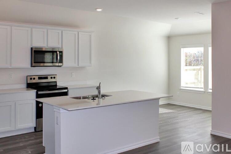 A kitchen with white cabinets and a white island with a sink.