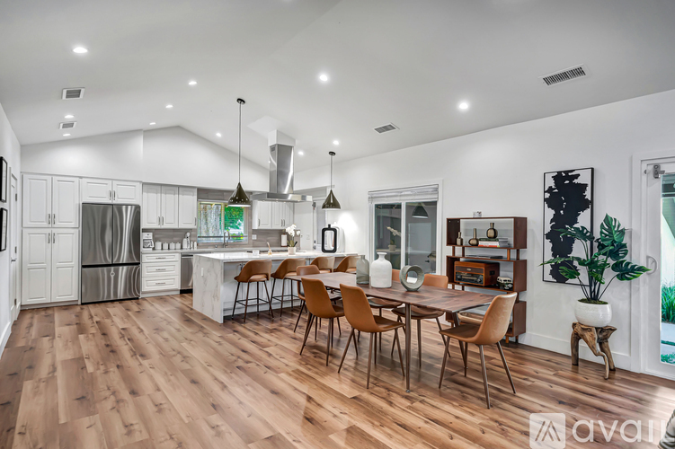 A modern kitchen with wooden floors and a dining table set for four.